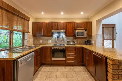 a kitchen with wooden cabinets and a stove top oven at Kruger Park Lodge Unit No 237 in Hazyview