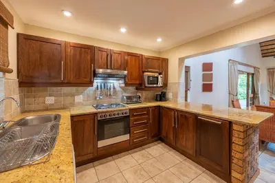 a kitchen with wooden cabinets and a stove top oven at Kruger Park Lodge Unit No 237 in Hazyview