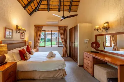 a bedroom with a large bed and a desk at Kruger Park Lodge Unit No 237 in Hazyview