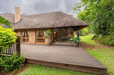 a house with a thatched roof and a wooden deck at Kruger Park Lodge Unit No 237 in Hazyview
