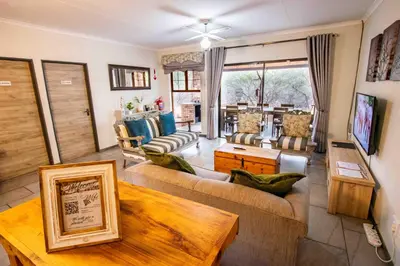 a living room with couches and a table at Manor by My Adventure House in Marloth Park