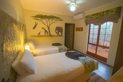 a hotel room with two beds and a window at Manor by My Adventure House in Marloth Park