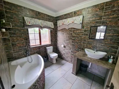 a bathroom with a tub and a sink and a toilet at Manor by My Adventure House in Marloth Park