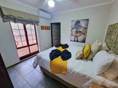 a bedroom with a bed with yellow and blue towels on it at Manor by My Adventure House in Marloth Park