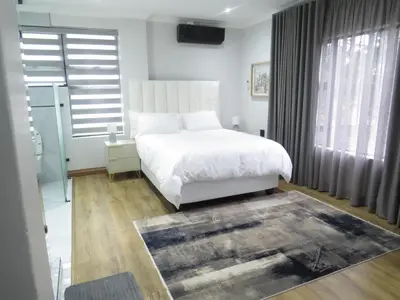 a bedroom with a white bed and a large window at Thaba Bosiu Villa in Naboomspruit