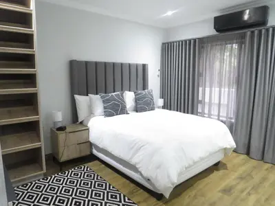 a bedroom with a white bed and a large window at Thaba Bosiu Villa in Naboomspruit