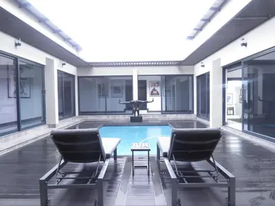 a pool with two chairs and a table in a building at Thaba Bosiu Villa in Naboomspruit