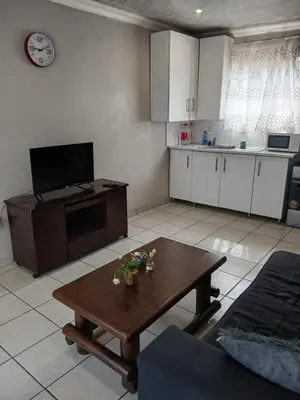 a living room with a table and a kitchen at Thonta house in Pretoria