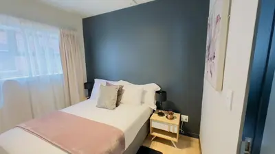 a bedroom with a bed and a blue wall at Urban Oasis Retreat in Midrand in Midrand