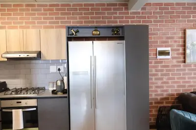 a stainless steel refrigerator in a kitchen with a brick wall at Urban Oasis Retreat in Midrand in Midrand