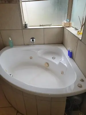 a bath tub with a sink and a mirror at Peshi's Guest House in Pretoria