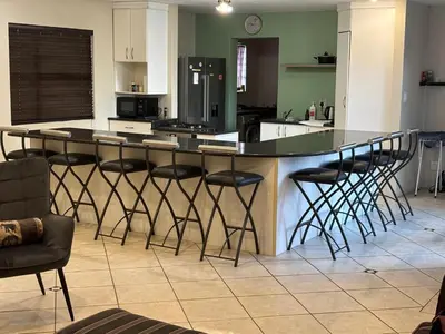 a kitchen with a bar with stools around it at Peshi's Guest House in Pretoria