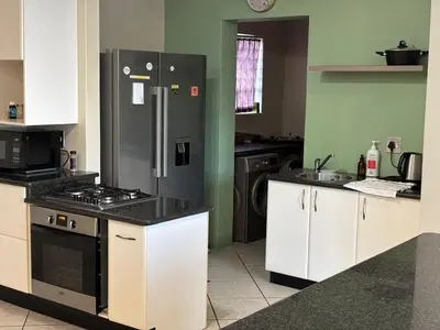 a kitchen with white cabinets and a black refrigerator at Peshi's Guest House in Pretoria