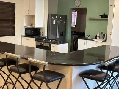 a kitchen with a black counter and stools in it at Peshi's Guest House in Pretoria