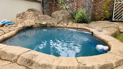 a large pool of water with a rock around it at Peshi's Guest House in Pretoria