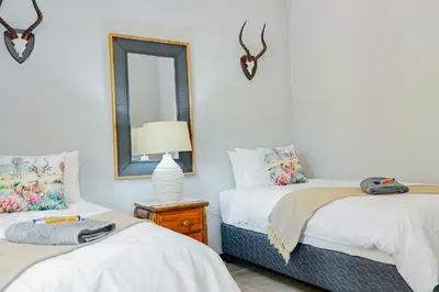 two beds in a room with a mirror and a lamp at Stripes & Sunsets Marloth Park - Self catering, Bush retreat With Pool & Wildlife views Near Kruger Park in Marloth Park