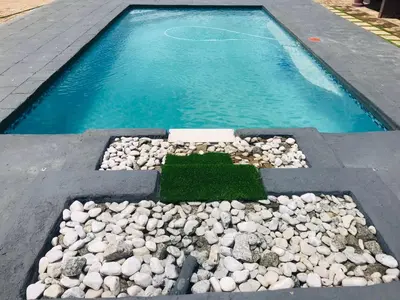 a pool of water with rocks and green grass at RMB Luxury Lodge in Polokwane