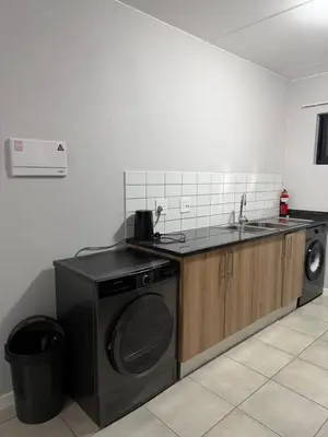 a kitchen with a washing machine and a sink at Elevare suites in Nelspruit