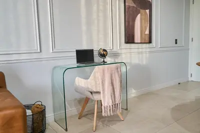 a glass table with a chair with a laptop on it at Hidden Diamond at Ellipse Waterfall in Midrand