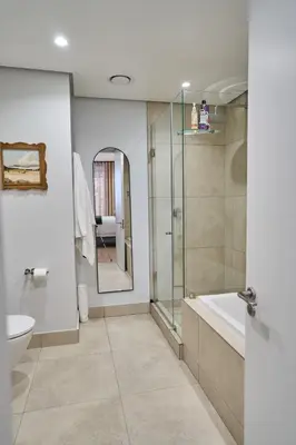 a bathroom with a shower and a toilet and a sink at Hidden Diamond at Ellipse Waterfall in Midrand