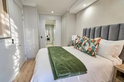 a bedroom with a large white bed with a gray headboard at Hidden Diamond at Ellipse Waterfall in Midrand