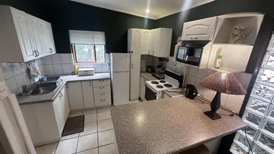a small kitchen with white appliances and a lamp at Cabin & Cottage Kaapsehoop in Kaapsehoop