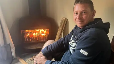 a man sitting in a chair in front of a fireplace at Cabin & Cottage Kaapsehoop in Kaapsehoop