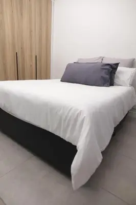 a large bed with white sheets and gray pillows at Waterfall Munyaka Estate in Midrand