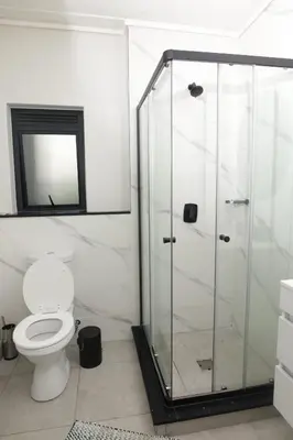 a bathroom with a toilet and a glass shower at Waterfall Munyaka Estate in Midrand