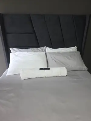 a white bed with a black headboard and white pillows at The Good Samaritan 1 in Witbank