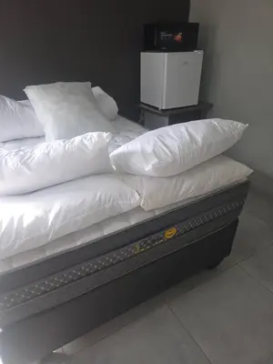 a bed with white sheets and pillows on it at The Good Samaritan 1 in Witbank