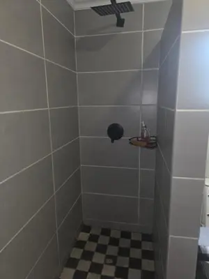 a tiled shower with a black and white checkered floor at The Good Samaritan 1 in Witbank