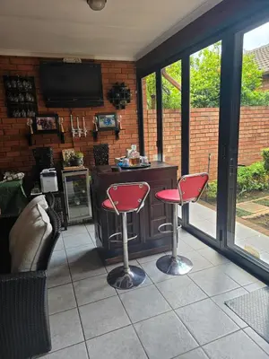 a patio with two red chairs and a bar at Entire Home - Relax - Work - Entertain - Private in Centurion