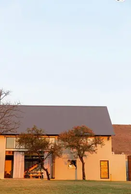 a building with a black roof and two trees at House Nyala in Lydenburg
