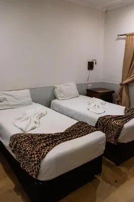 two beds in a room with a leopard print blanket at Kambaku II Boat Safaris & Lodge in Phalaborwa