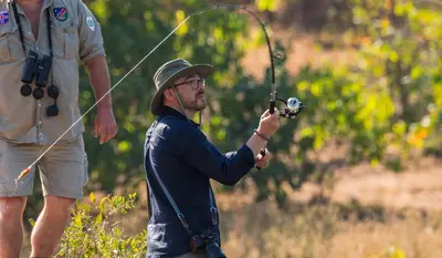 a man holding a fishing rod with a man at Kambaku II Boat Safaris & Lodge in Phalaborwa
