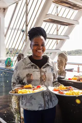 a woman is holding two plates of food at Kambaku II Boat Safaris & Lodge in Phalaborwa