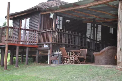 a large wooden cabin with chairs and a table at Gunyatoo Trout Trout Farm & Guest Lodge in Sabie