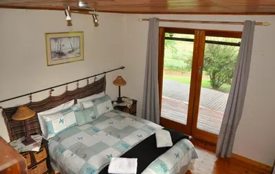 a bedroom with a bed and a sliding glass door at Gunyatoo Trout Trout Farm & Guest Lodge in Sabie