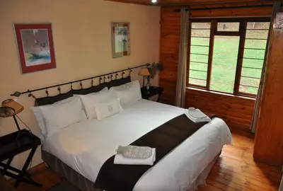 a bedroom with a large white bed in a cabin at Gunyatoo Trout Trout Farm & Guest Lodge in Sabie