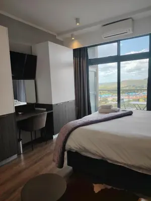 a hotel room with a bed and a desk and a window at Menlyn Maine Trilogy Apartment 914A in Pretoria