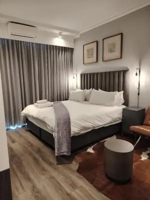 a bedroom with a large bed and a chair at Menlyn Maine Trilogy Apartment 914A in Pretoria