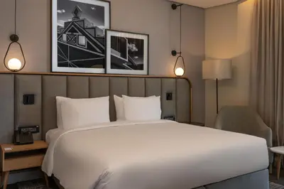 a bedroom with a large white bed and a chair at Radisson Hotel & Convention Center Steve Tshwete Middelburg in Middelburg