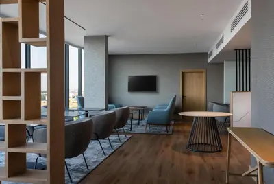 a waiting room with tables and chairs and a tv at Radisson Hotel & Convention Center Steve Tshwete Middelburg in Middelburg