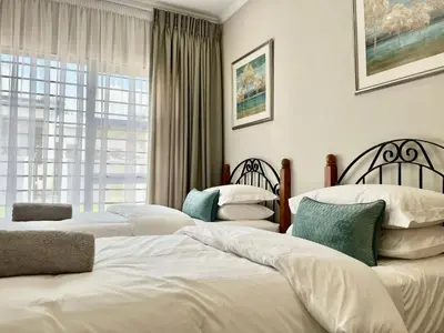 a bedroom with three beds and a window at Modern 2 Bedroom Apartment near Carstenhof Hospital, Glen Austin in Midrand