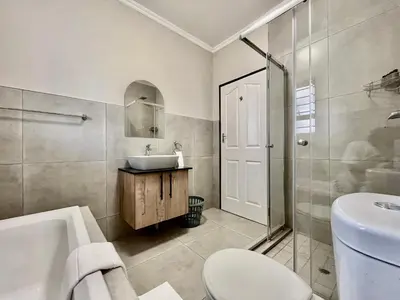 a bathroom with a sink and a toilet and a shower at Modern 2 Bedroom Apartment near Carstenhof Hospital, Glen Austin in Midrand