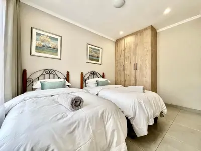 two beds with white sheets in a bedroom at Modern 2 Bedroom Apartment near Carstenhof Hospital, Glen Austin in Midrand