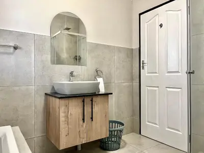 a bathroom with a sink and a mirror at Modern 2 Bedroom Apartment near Carstenhof Hospital, Glen Austin in Midrand