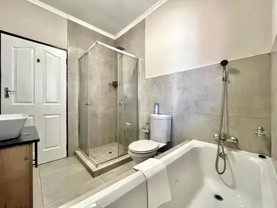 a bathroom with a tub and a toilet and a shower at Modern 2 Bedroom Apartment near Carstenhof Hospital, Glen Austin in Midrand