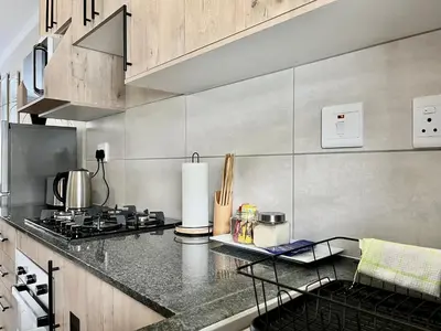 a kitchen with a stove and a counter top at Modern 2 Bedroom Apartment near Carstenhof Hospital, Glen Austin in Midrand